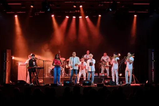 Les chanteurs de Nolosé en front de scène dans la lumière rouge du Stimmen Festival d'Ettiswil