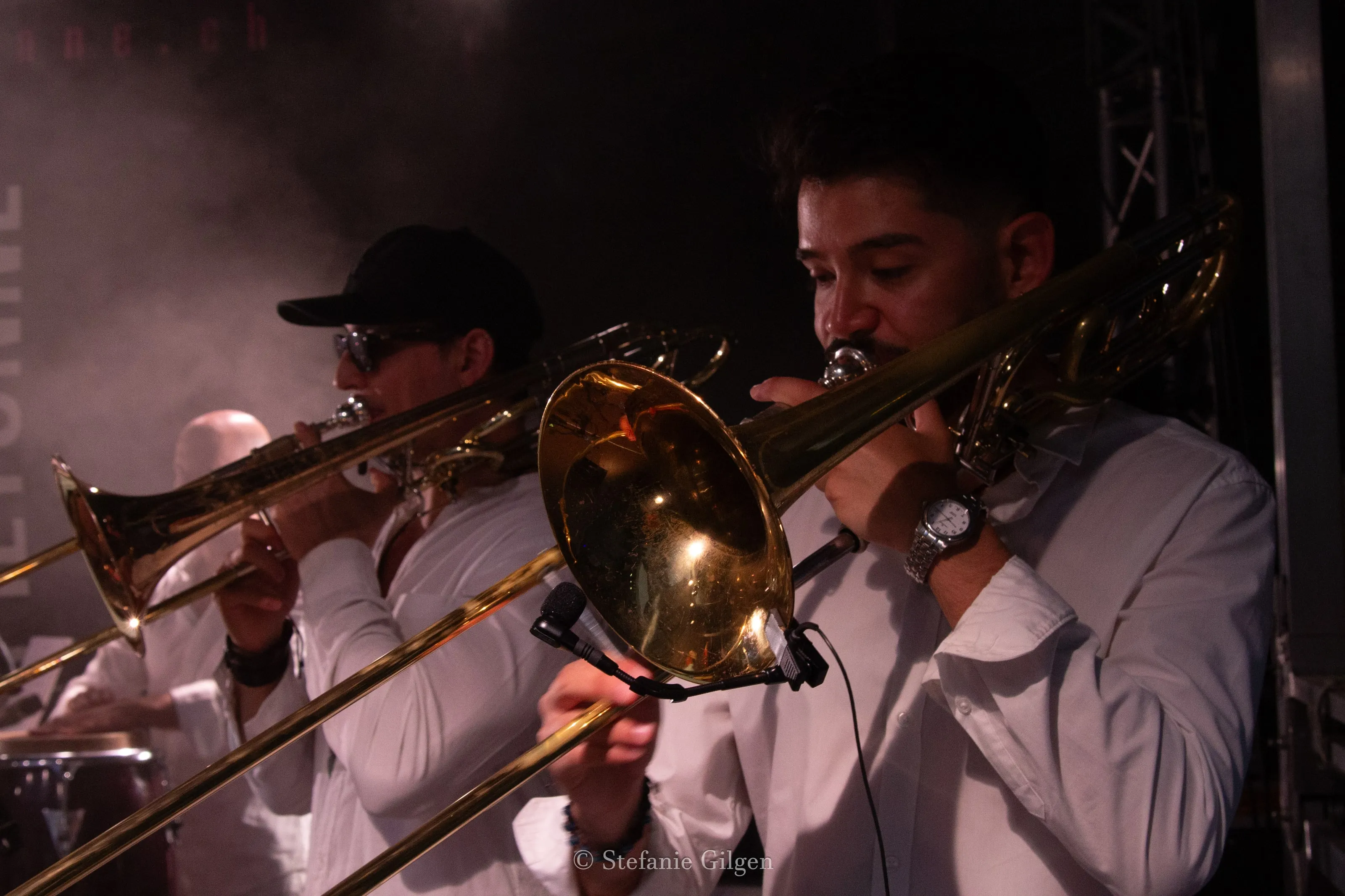 Deux trombonistes en chemises blanches, gros plan dans la fumée et la lumière du club — photo Stefanie Gilgen