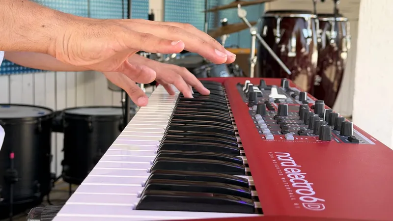 Mains sur le clavier rouge de Nolosé, congas en arrière-plan